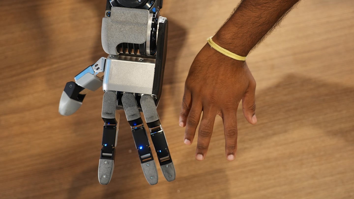 La mano GR3 de cuatro dedos de Atlas junto a una mano humana